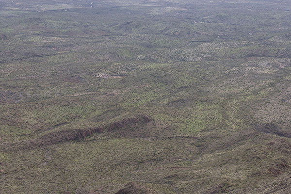Looking down towards my Jeep, a tiny black dot on a ridge just below and to the right of the dry watering hole